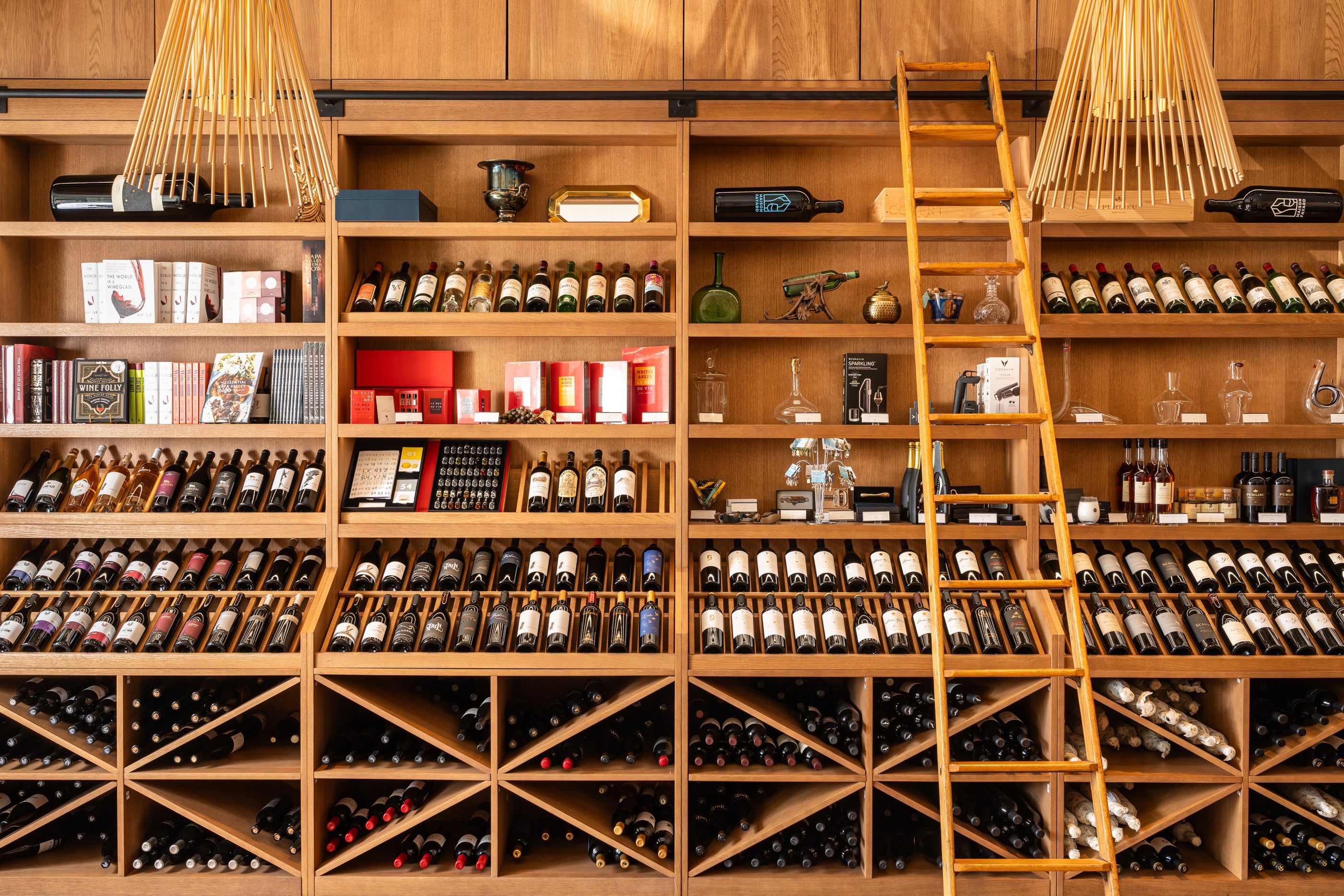 Wooden wine rack filled with various bottles of wine, with a ladder on the right.